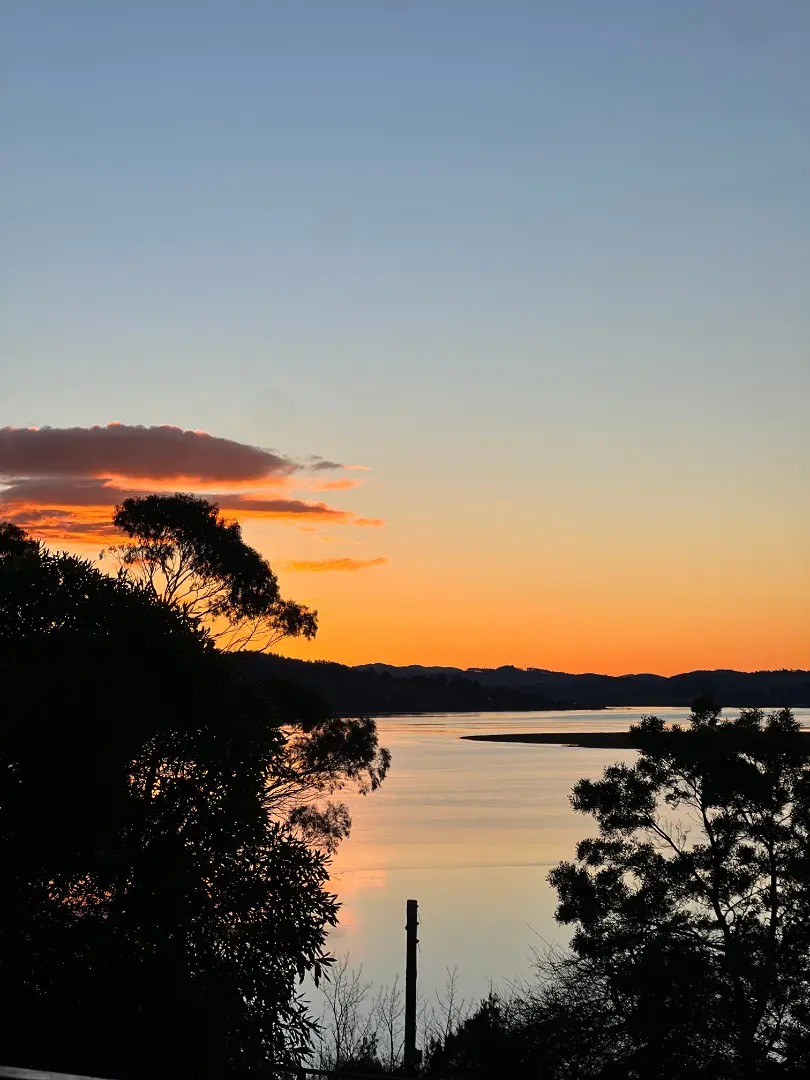 Serene sunset over calm waters and silhouettes.