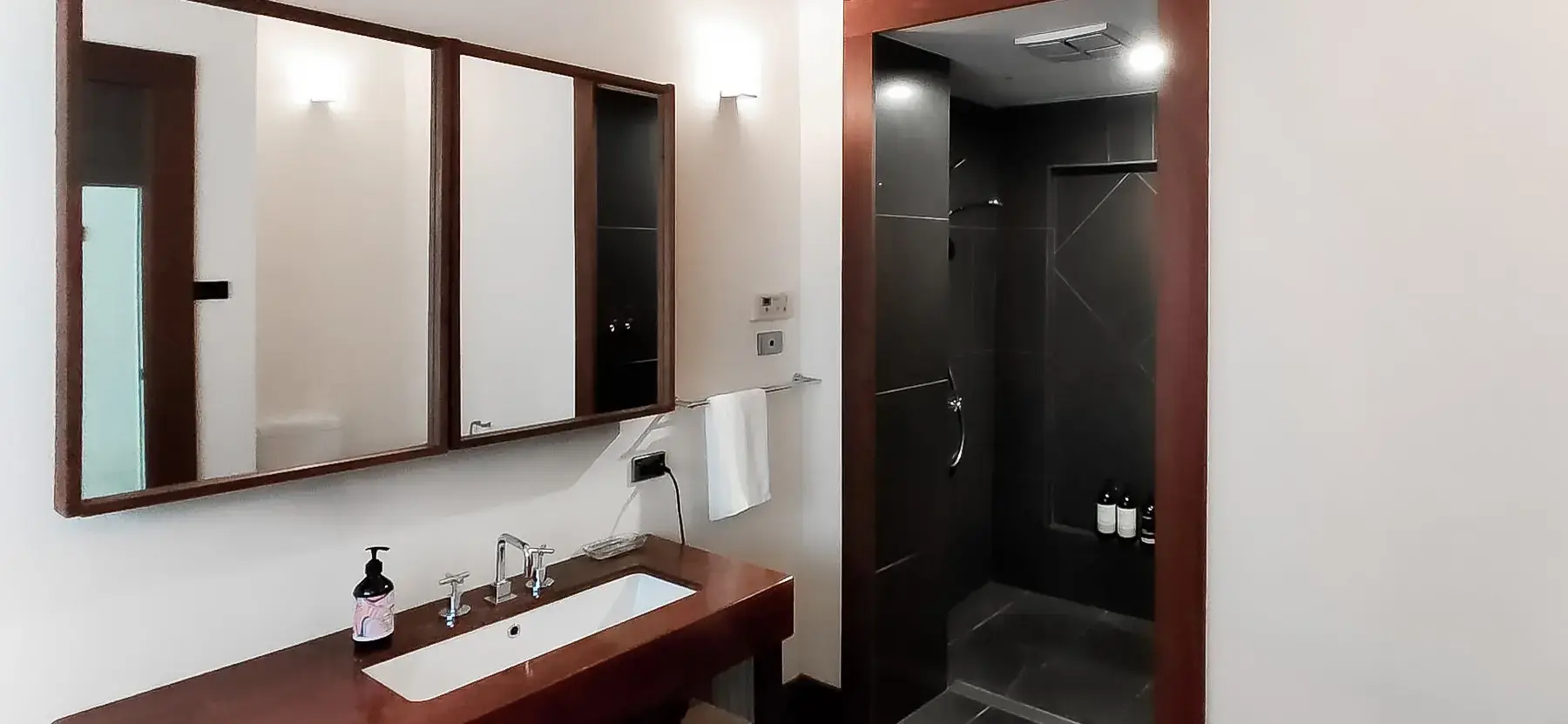 Modern bathroom with wooden vanity and dark shower