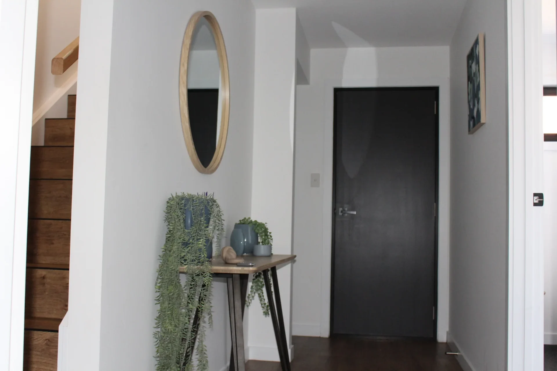 Modern hallway with mirror and greenery decor.