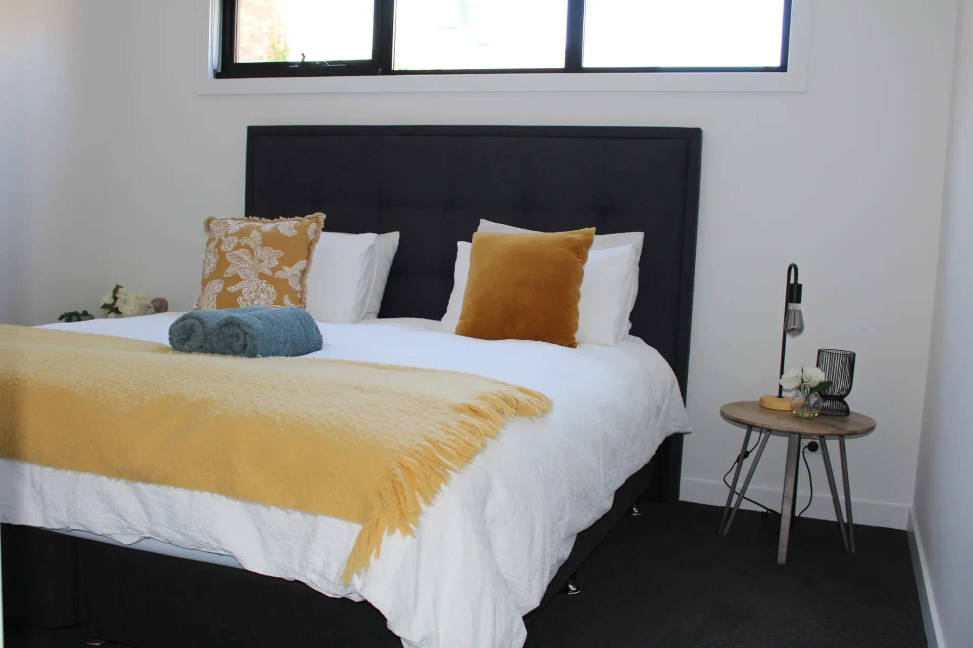 Cozy bedroom with yellow blanket and pillows.