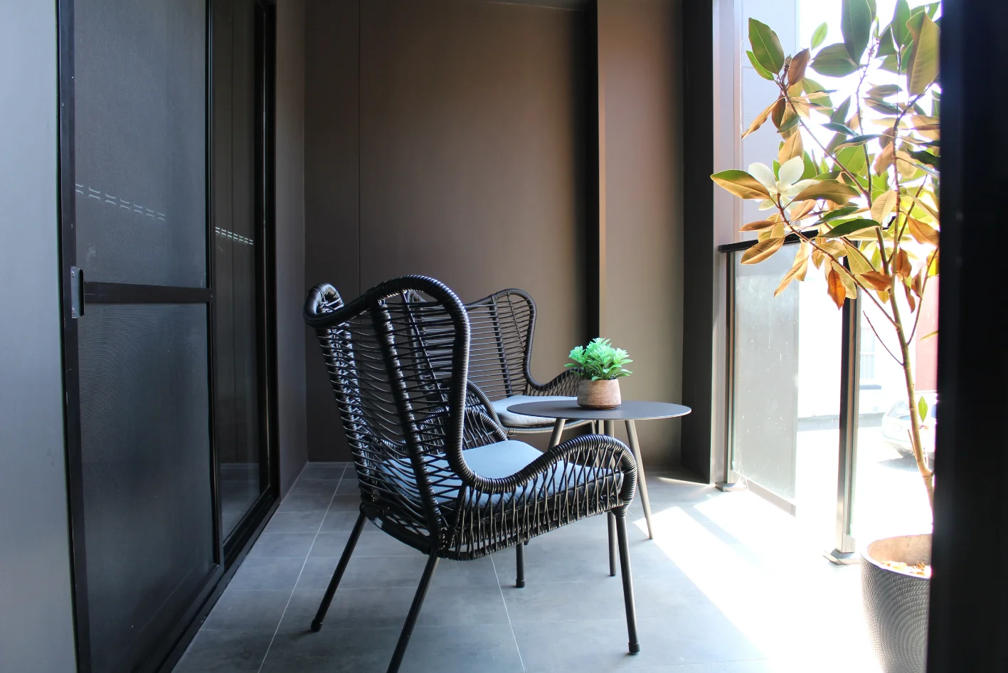 Cozy balcony with chairs and potted plant.