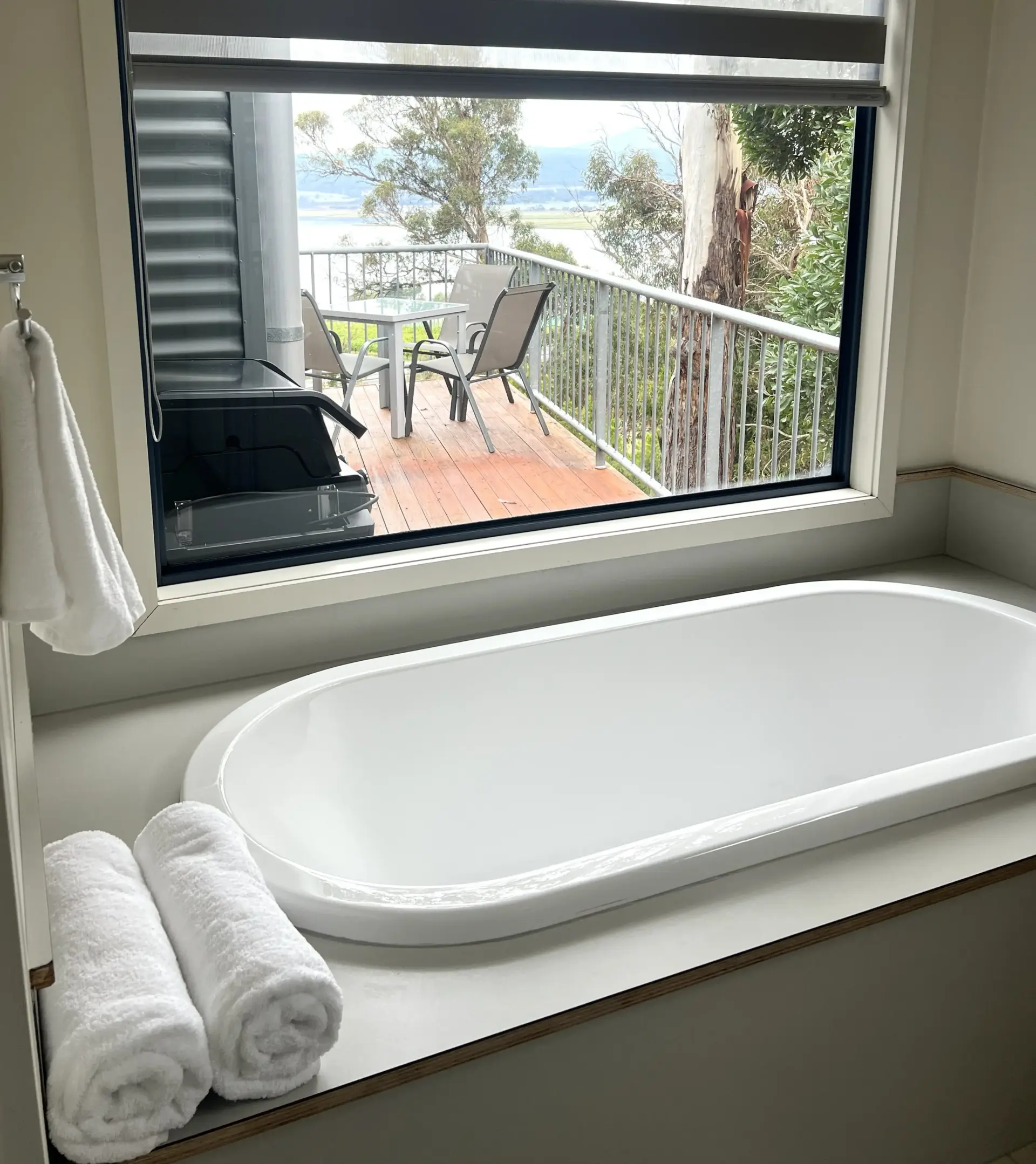 Bathtub overlooking balcony with water and trees