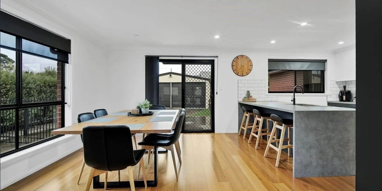 Modern dining area with kitchen and outdoor view.