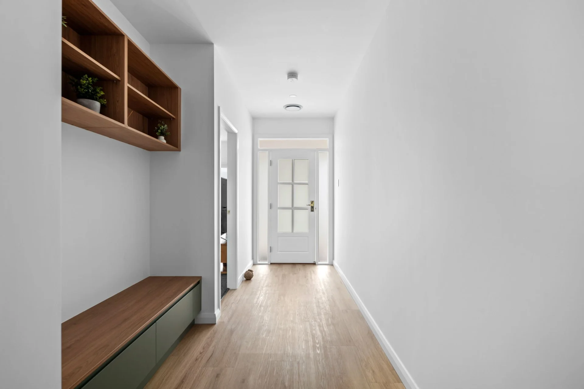 Bright hallway with wooden features and shelves.