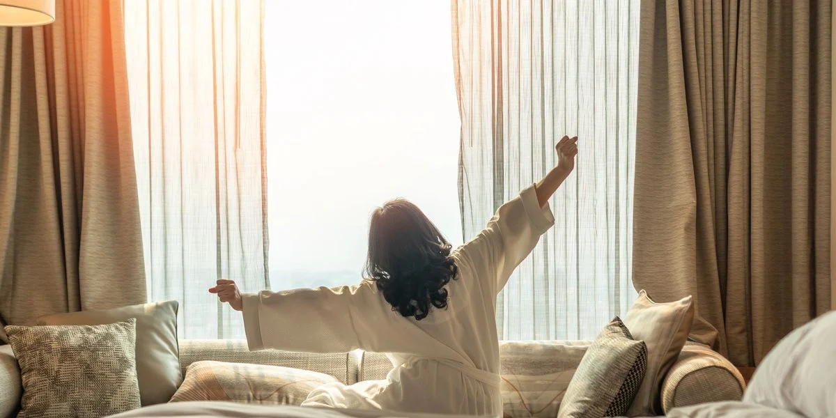 Person enjoying morning light in hotel room