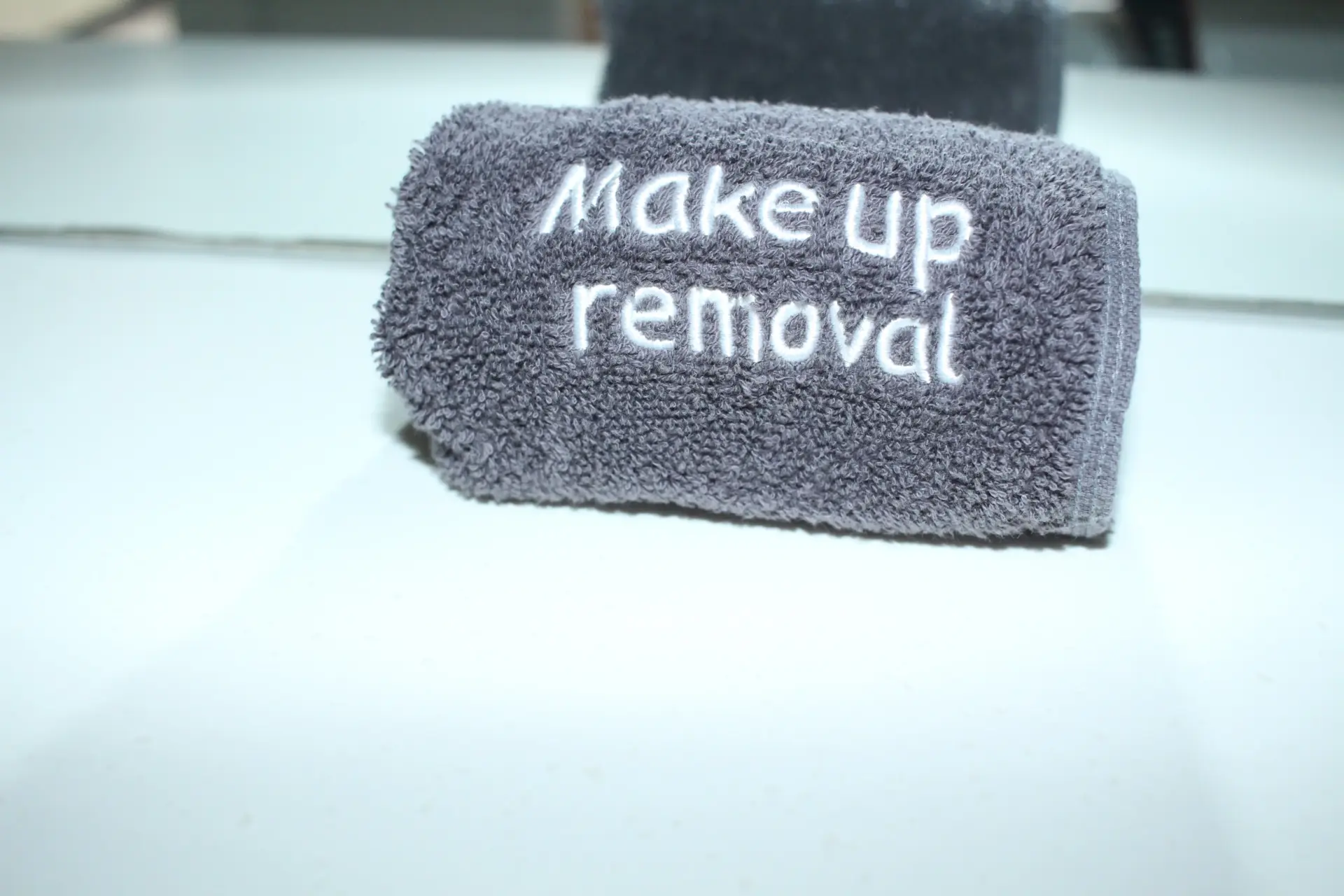 Grey towel embroidered with ‘Make up removal’