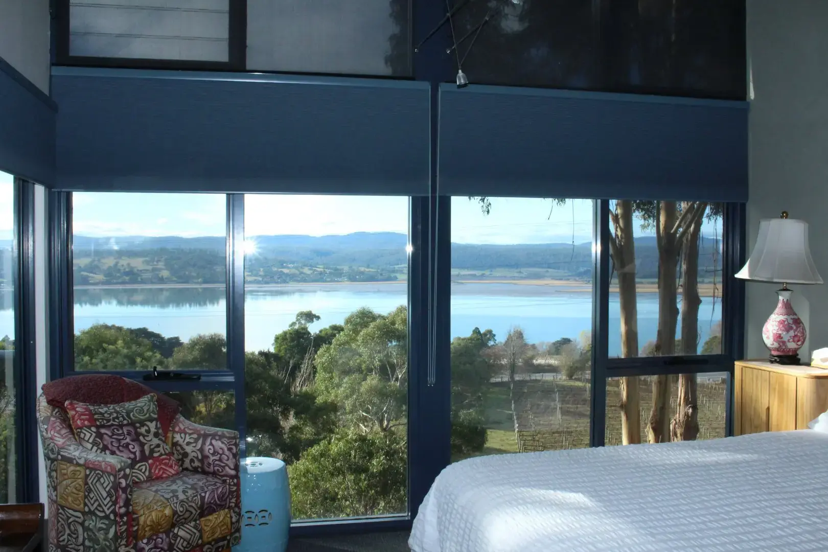 Bedroom with large windows overlooking river and hills
