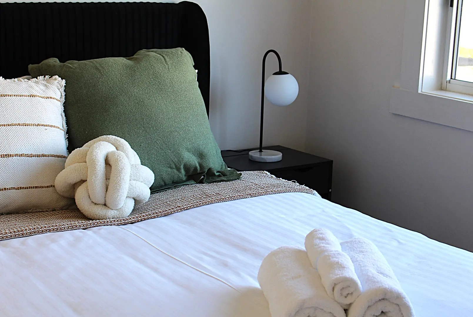 Stylish bedroom with pillows and rolled towels.