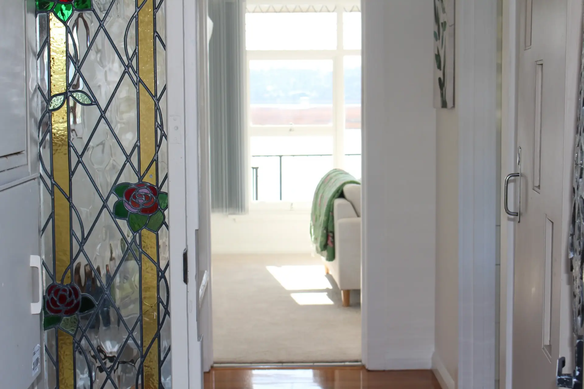 Hallway with stained glass and bright living room view.