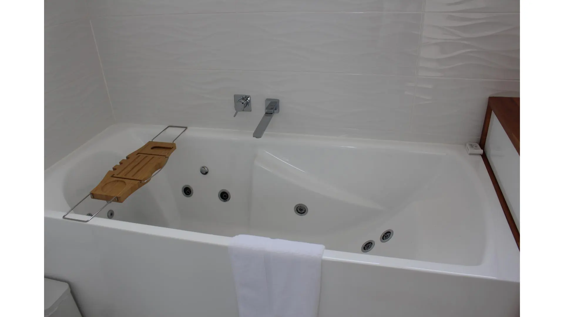 Modern spa bath with wooden bath tray.