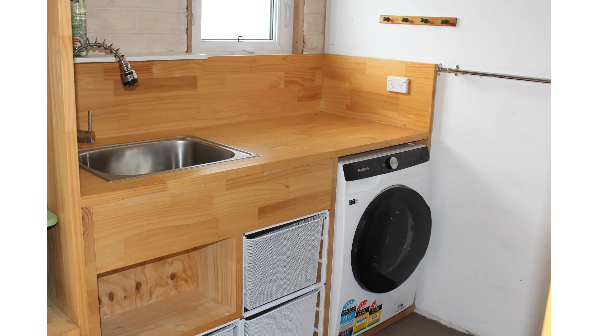 Laundry area with wooden countertop and washing machine.