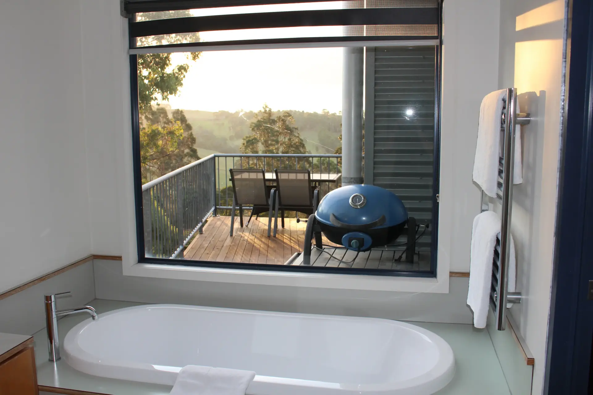 Bathtub overlooking balcony with grill and bushland view