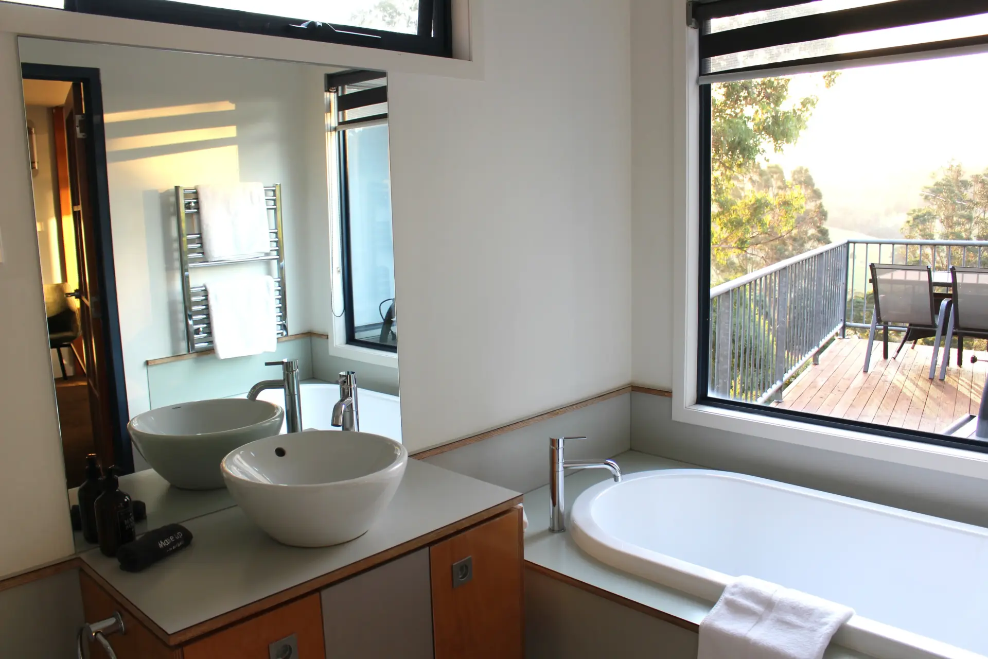 Modern bathroom with bathtub overlooking leafy balcony