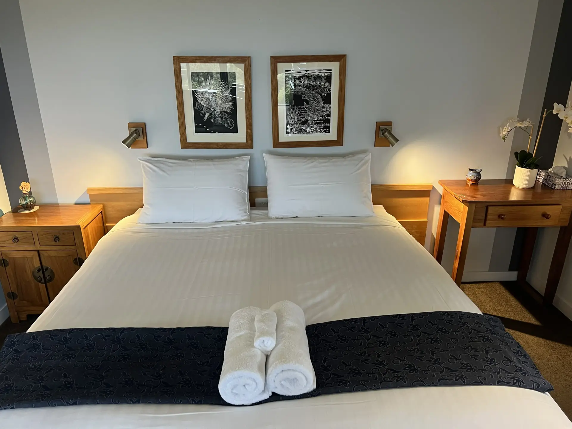 Neat bedroom with wooden furniture and framed artwork
