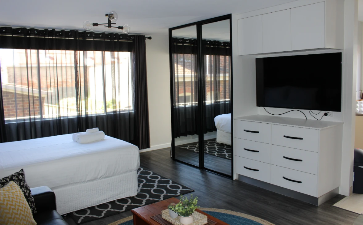 Modern bedroom with window, TV, and mirror.