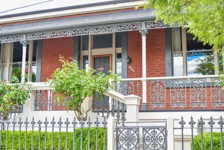 Victorian red brick house with ornate iron veranda
