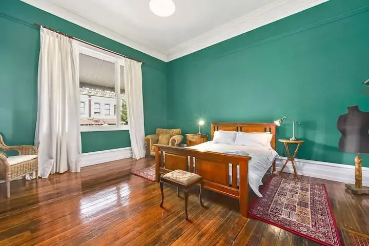 Spacious bedroom with green walls and wooden floors
