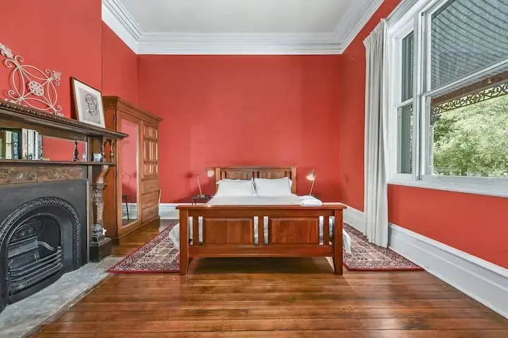 Red-walled bedroom with wooden bed and fireplace