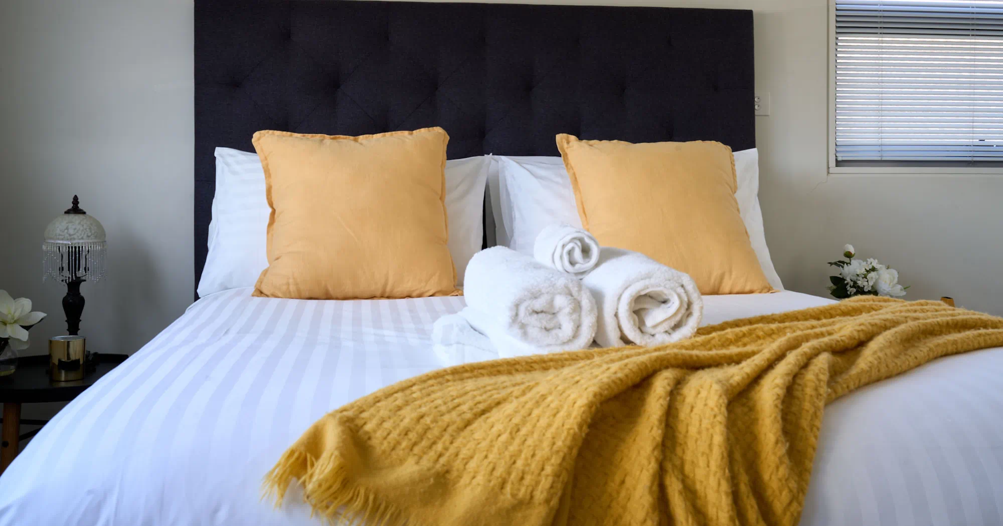 Cozy bed with yellow pillows and towels