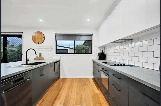 Modern kitchen with grey cabinetry and wooden floors.