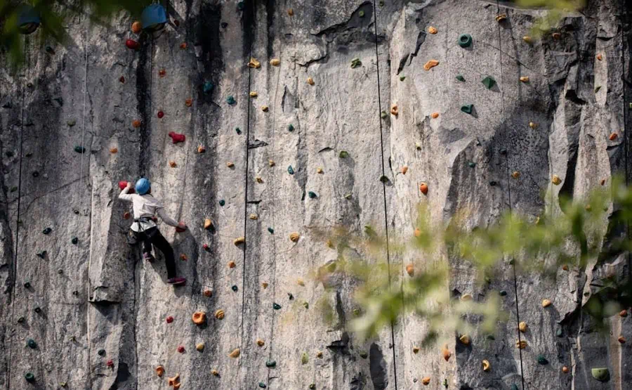 Climber scaling a rock climbing wall outdoors.