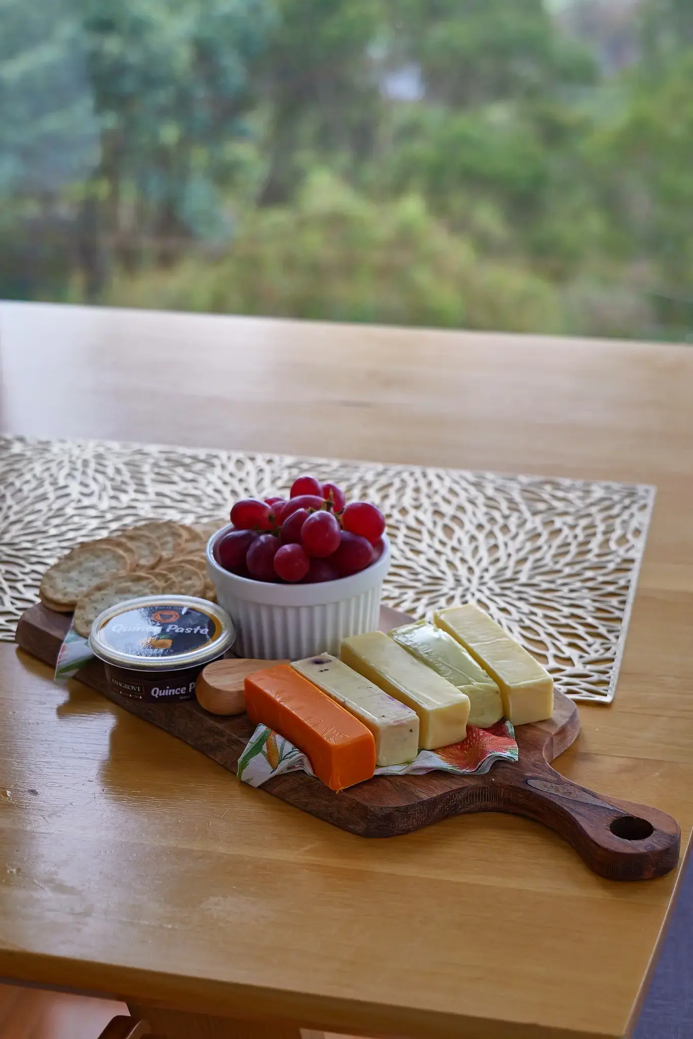 Cheese board with grapes, crackers and quince paste