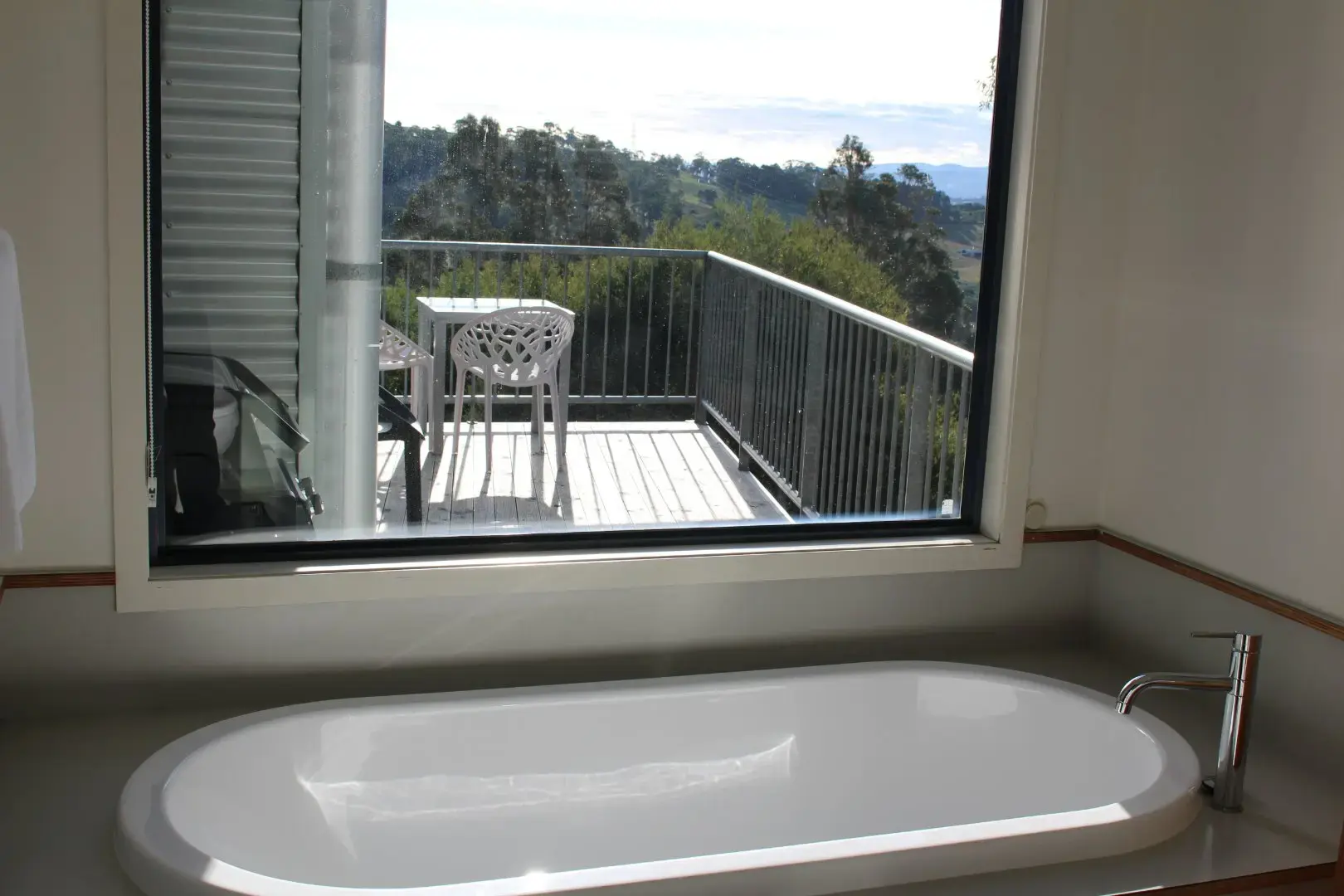 Bathtub with window view to balcony and hills