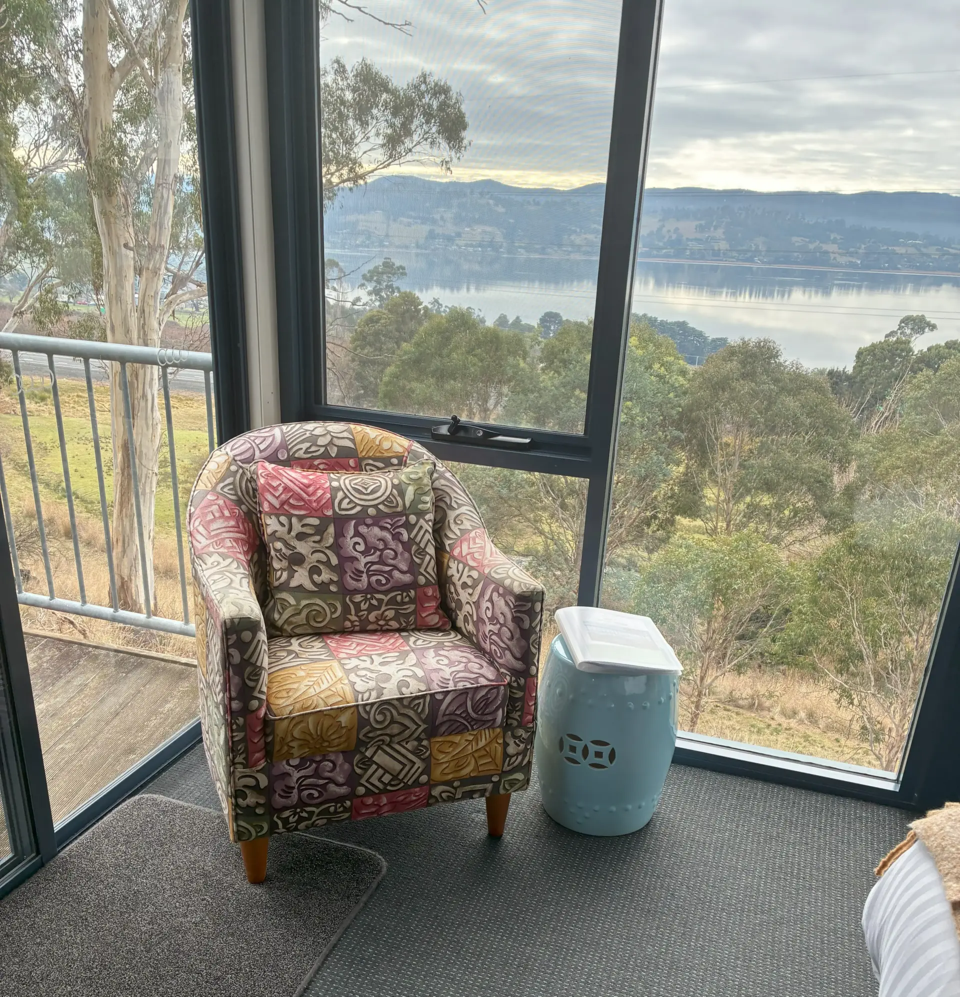 Patterned armchair by window overlooking river and hills